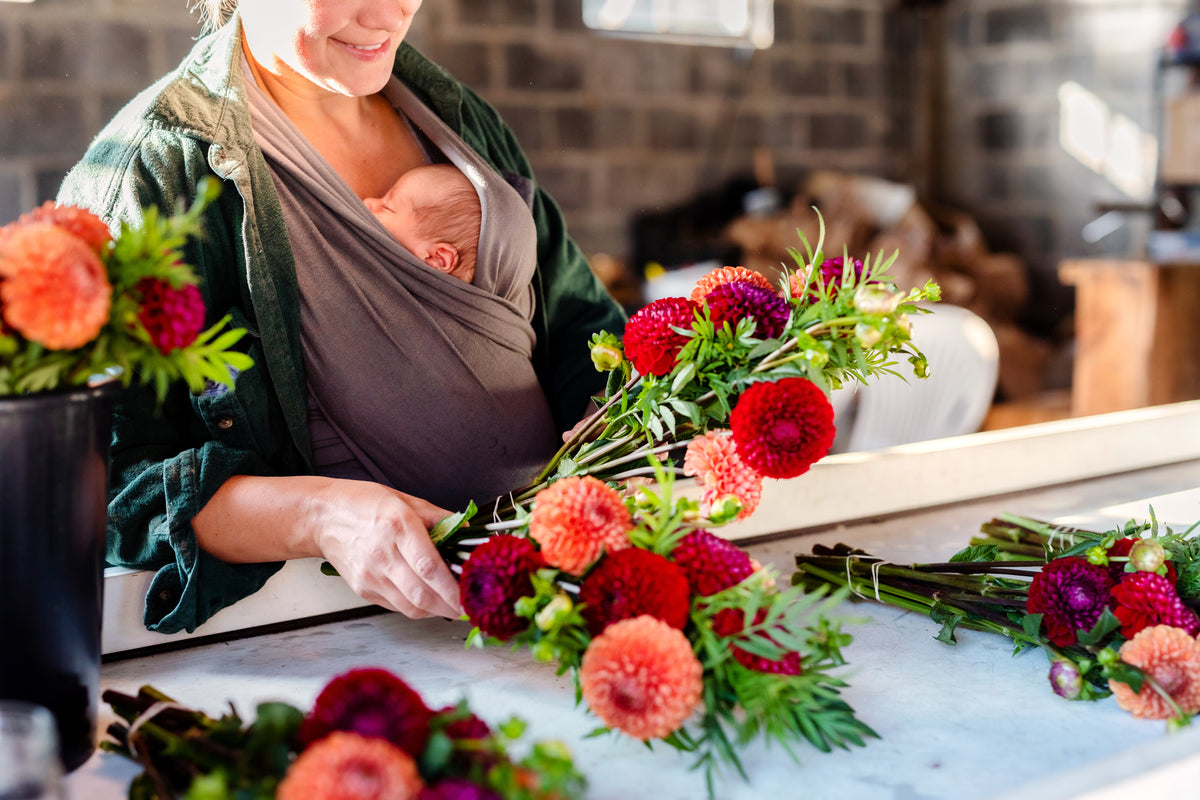 Becky making a mixed dahlia bouquet while carrying her baby at Rooted Flowers
